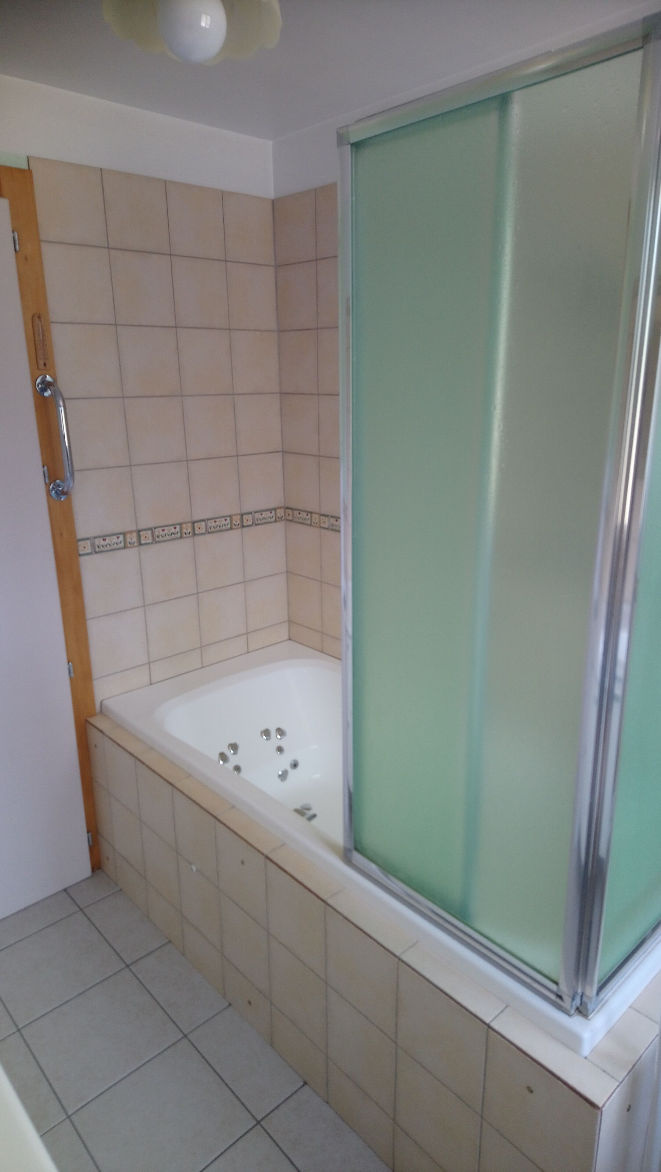 Une salle de bain avec une baignoire, un espace douche et des murs carrelés.
