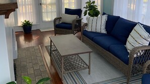A living room with a blue sofa, wicker chairs, a wooden coffee table, and a chandelier. - Historical Natchitoches Home, close to downtown and Cane River. (Natchitoches)