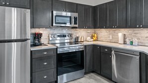 A modern kitchen with dark cabinets, stainless steel appliances including a refrigerator, microwave, oven, and dishwasher. - Deluxe Golf Condo with Private, Covered Balcony - BEAUTIFUL View of the Ozarks (Branson)