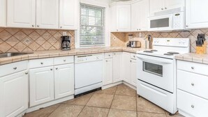 A kitchen with white cabinets, a microwave, a stove, and a dishwasher. - Bikini Bottom by Tybee Vacation Rentals (Tybee Island)