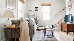 A living room with a sofa, a coffee table, a lamp, and a TV.