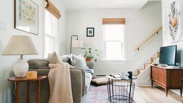 Un salon avec un canapé, une table basse, une lampe et un téléviseur.