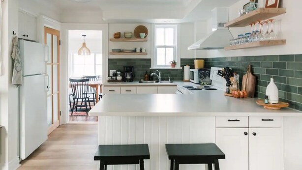 A modern kitchen with white cabinetry, a central island, and wooden shelves above the counter.