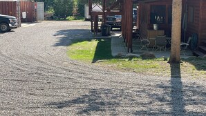 Uma entrada de cascalho leva a uma cabana de madeira com área de estar coberta ao ar livre.