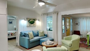 Una sala de estar moderna con un sofá azul, un sillón verde y una mesa de centro blanca.