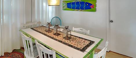 Un coin repas comprenant une table, des chaises, un luminaire suspendu et un décor mural représentant des poissons.