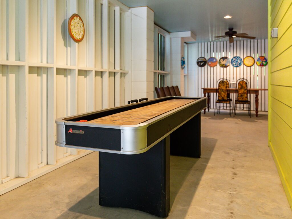 A pool table in a room with a white and yellow color scheme, a ceiling fan, and a wall with decorative plates.
