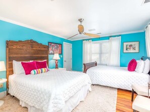 A bedroom with two beds, a ceiling fan, and a window with curtains. - Blue Skies by Tybee Vacation Rentals (Tybee Island)