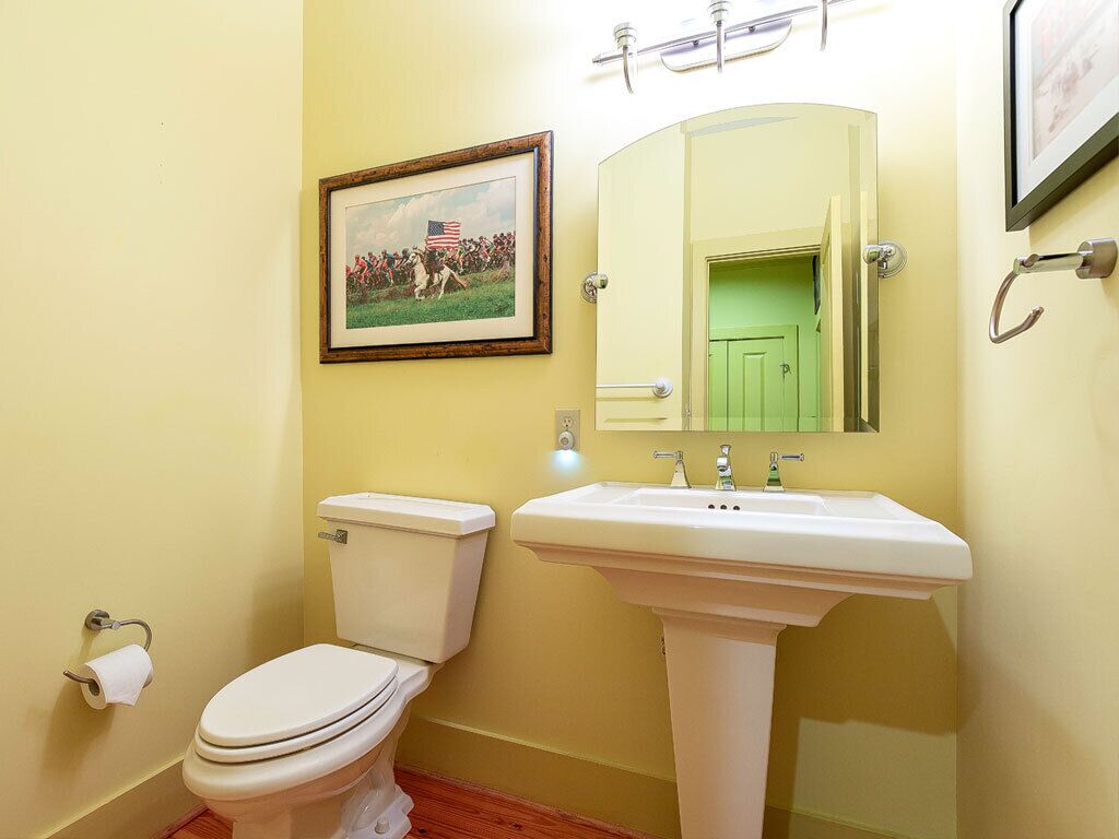 A bathroom with a toilet, sink, and a framed picture on the wall.