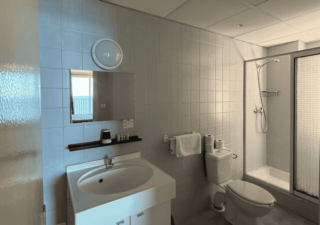 Ein modernes Badezimmer mit Waschbecken, Toilette und Dusche, alles in Weiß.