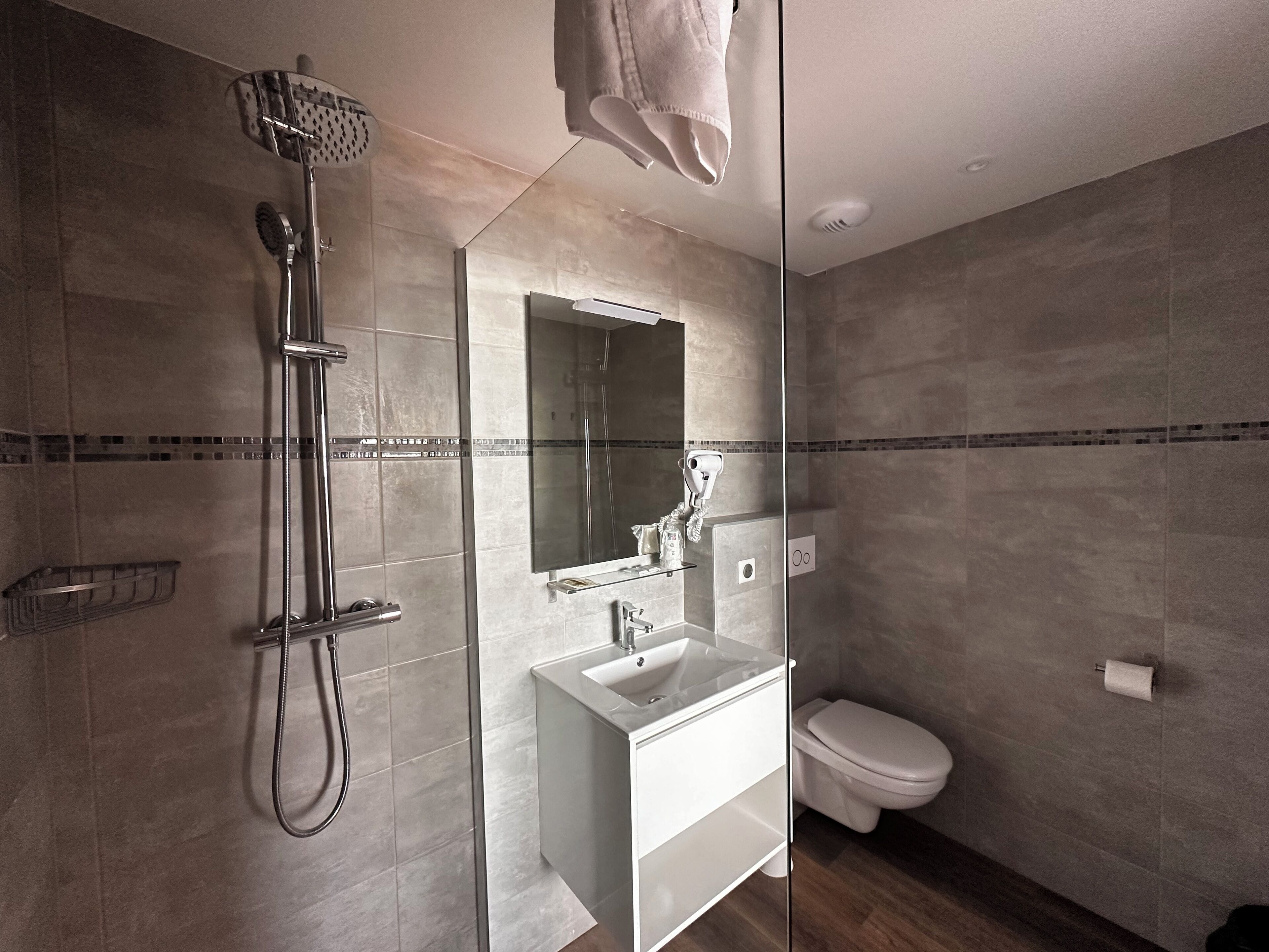 Un baño moderno con ducha de vidrio, lavamanos blanco y un inodoro.
