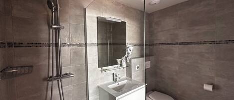 Un baño moderno con ducha de vidrio, lavamanos blanco y un inodoro.