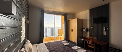 Habitación de hotel con cama, escritorio, silla, armario y televisor.