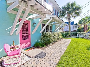 Charming single-story building with a vibrant facade, shaded entrance, and inviting outdoor seating area.