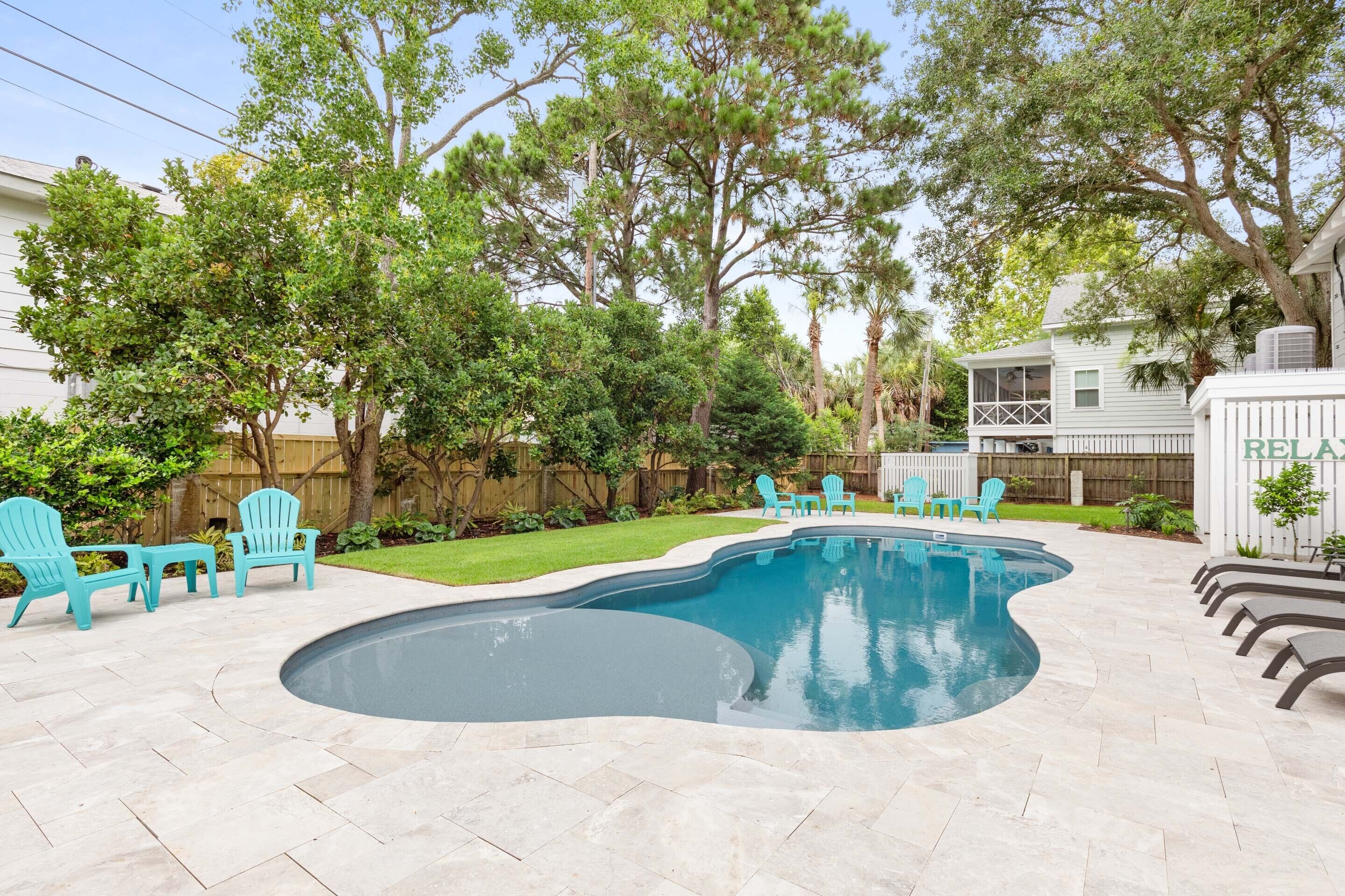A backyard with a swimming pool, outdoor furniture, and a wooden fence.