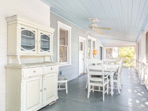 Relax and dine al fresco on this charming porch with a central fan, comfortable seating, and a dining table.