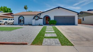 Une maison moderne de plain-pied avec un garage, une allée menant à une entrée bordée d’un chemin en briques et une petite pelouse.