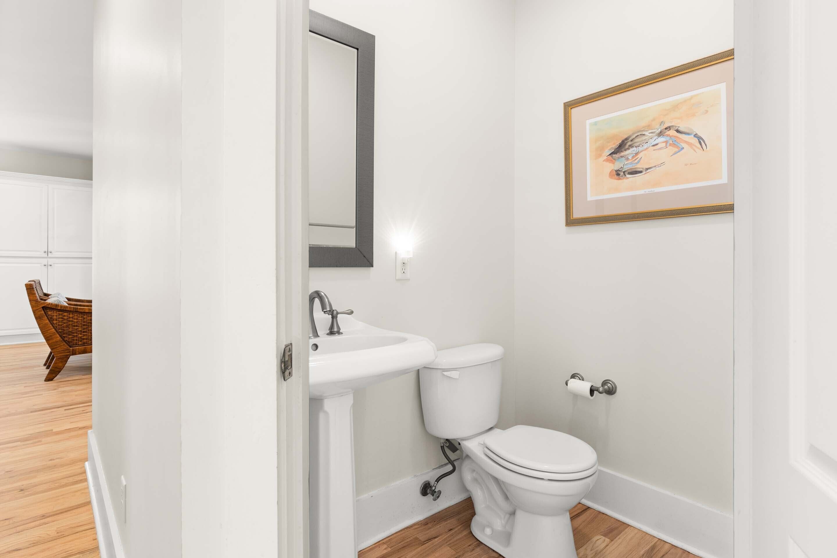 A bathroom with a white sink, toilet, and a framed artwork on the wall.