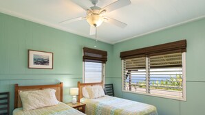 A room with two beds, a ceiling fan, a window with blinds, and a framed picture on the wall. - Cozy Cottage in Honoka'a with ocean view from front Lani. (Honokaa)