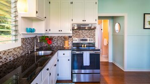 A modern kitchen with white cabinets, a stainless steel oven, and a brick backsplash. - Cozy Cottage in Honoka'a with ocean view from front Lani. (Honokaa)