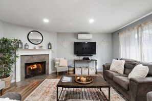 Una sala de estar con chimenea, sofá, una mesa de centro y televisión.