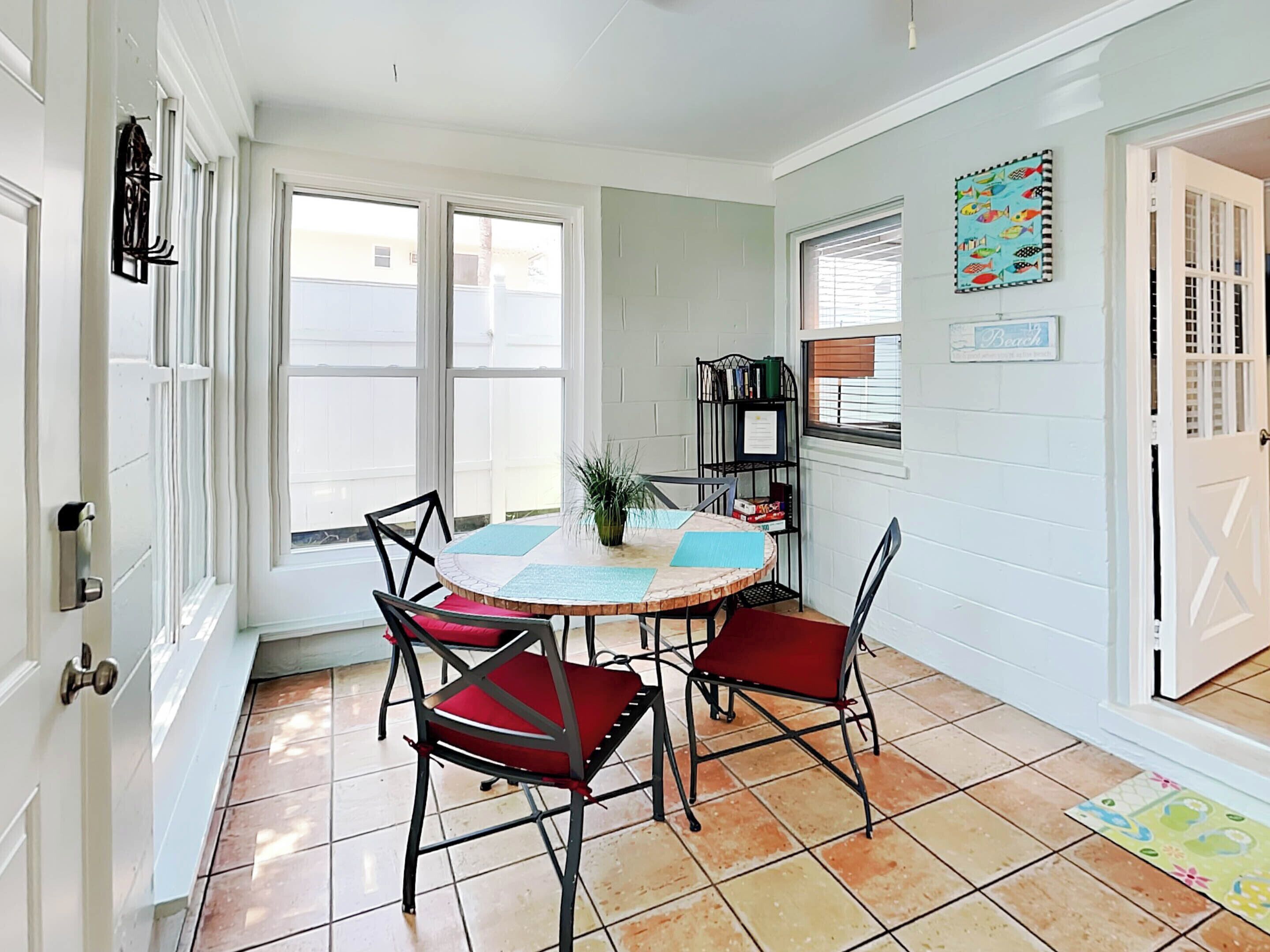 A dining area with a round table, four chairs, and a bookshelf.