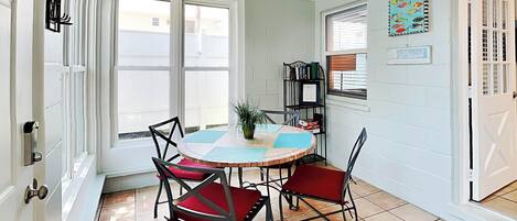 A dining area with a round table, four chairs, and a bookshelf.