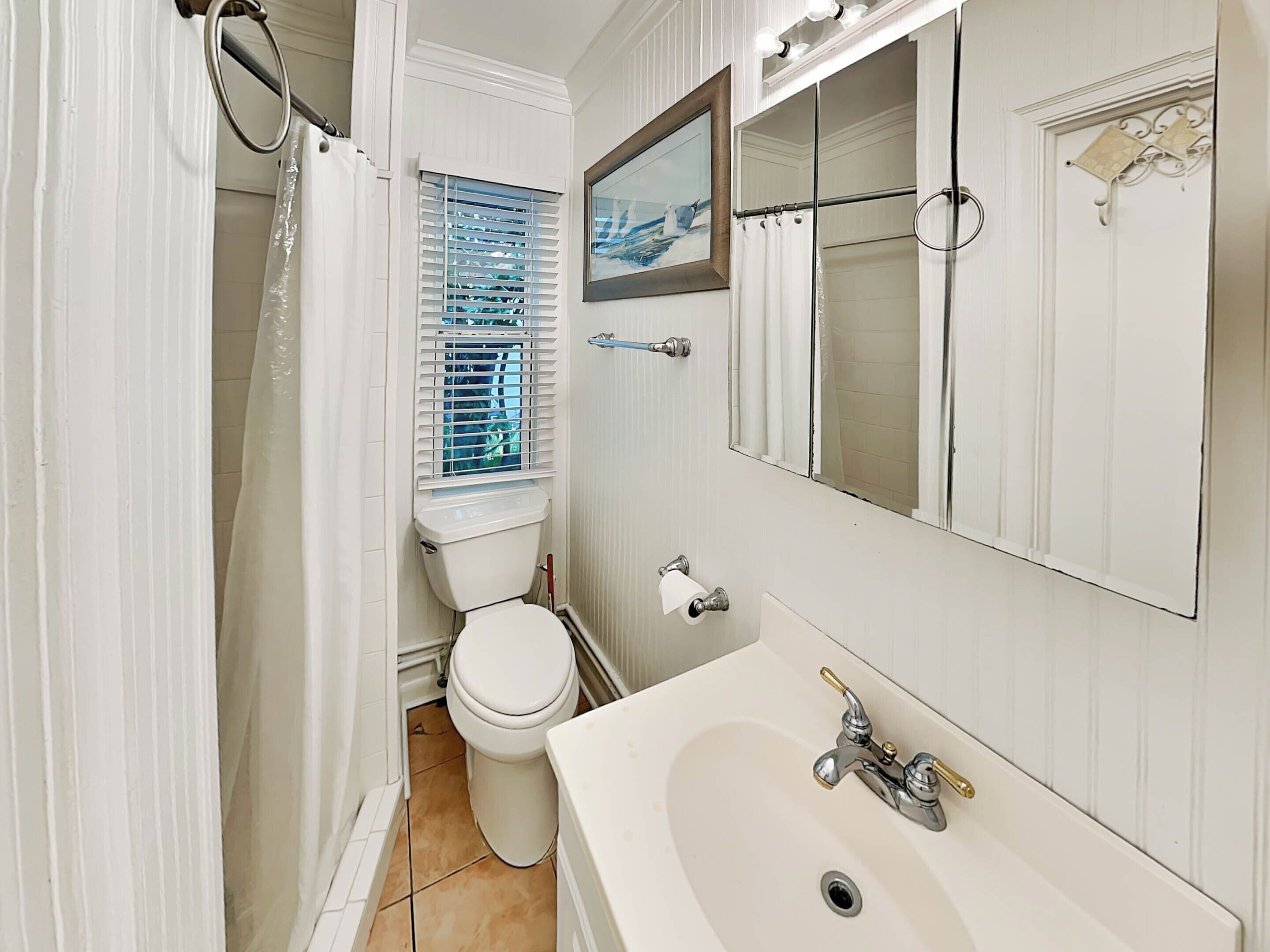 Ein Badezimmer mit Toilette, Waschbecken und einem Fenster mit Jalousien.