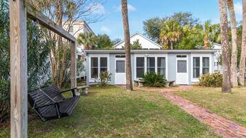 Family-friendly home surrounded by a lush garden and a wooden swing set.