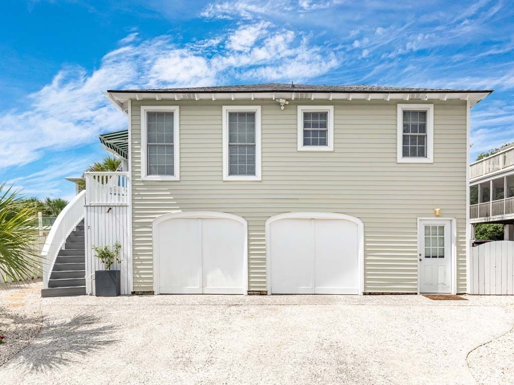 A two-story house with a front porch, a staircase, and two garage doors.