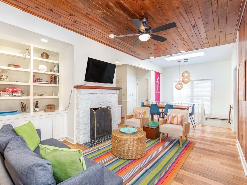Un salon avec une cheminée, un téléviseur et un ventilateur de plafond.