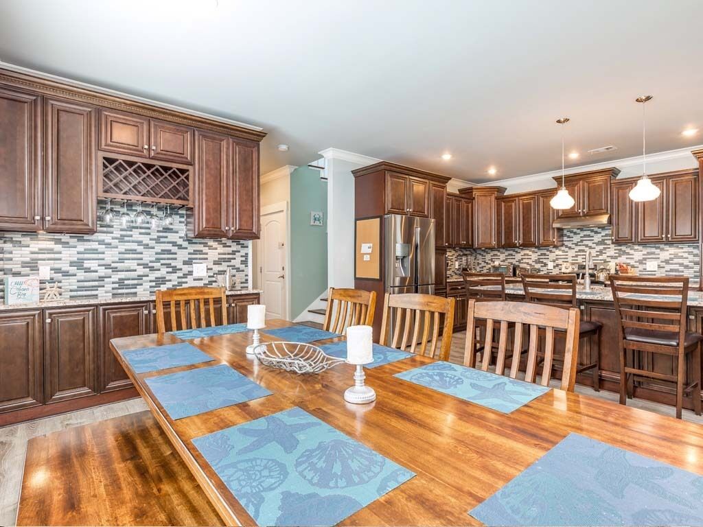 Eine moderne Küche mit dunklen Holzsäulen, einer Fliesenküchenwand und einem Essbereich mit einem Holztisch und blauen Platzsets.