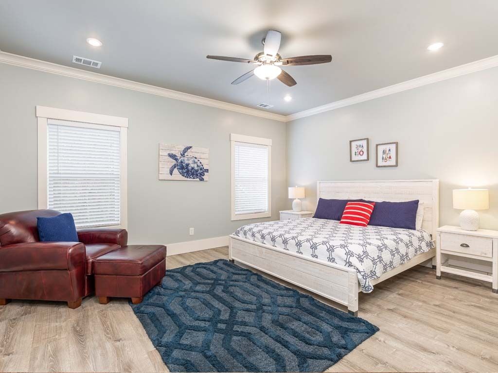 A bedroom with a bed, a nightstand, a chair, and a ceiling fan.