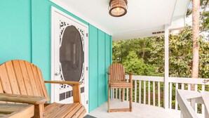 A wooden porch with a white railing, a wooden chair, and a bench. - Castaway Cottage by Tybee Vacation Rentals (Tybee Island)