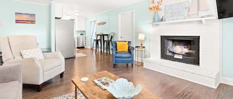 A living room with a fireplace, a ceiling fan, and a dining area with a table and chairs.