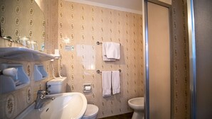 Une salle de bain comprenant un lavabo, des toilettes et un bidet, avec un papier peint à motifs et un porte-serviettes.