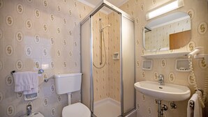 A bathroom with a toilet, bidet, sink, and a glass-enclosed shower.