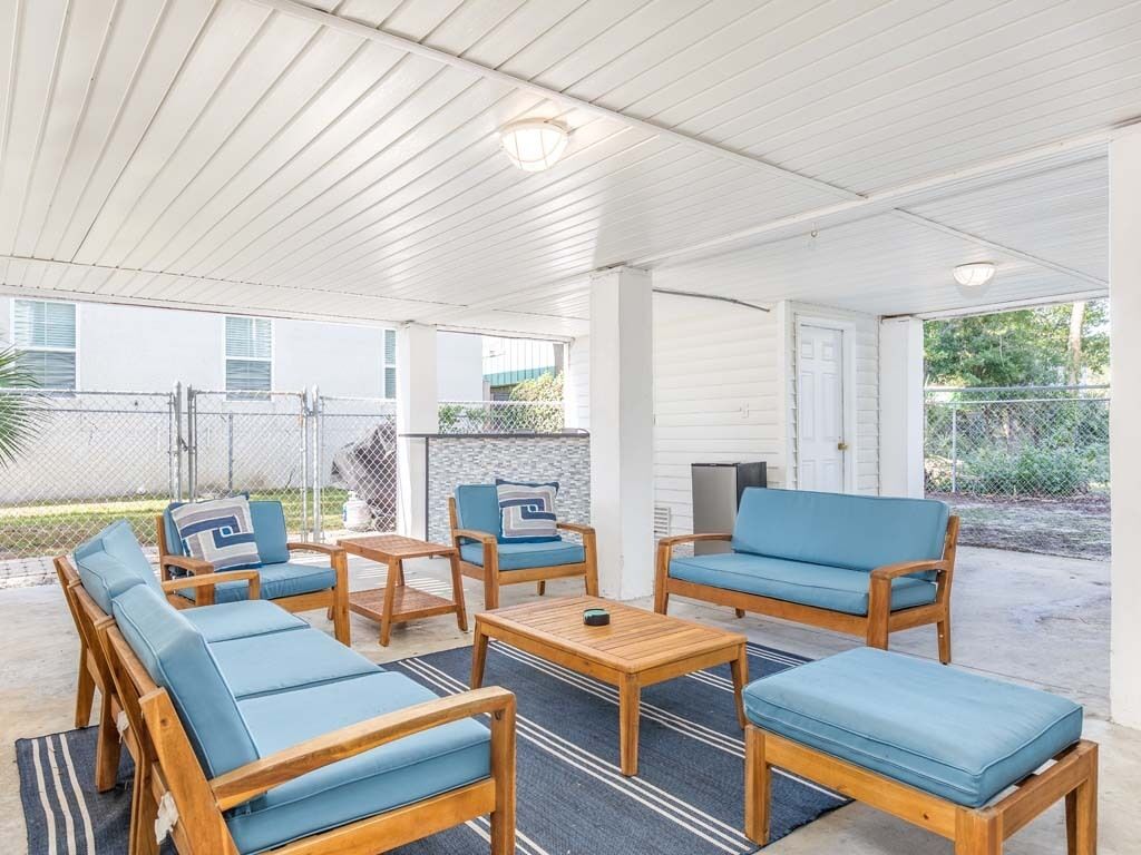 An outdoor patio area with wooden furniture, including sofas and chairs, and a small table.