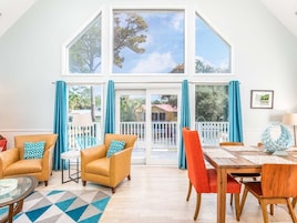 Un salón comedor amplio con techo alto, ventanas grandes y balcón. Hay dos sofás, una mesa de comedor y una mesa de centro.