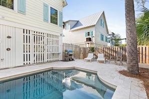 Relax in a serene backyard with a pool, grill, and lounge chairs.