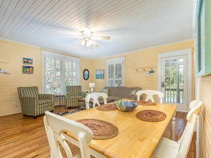 A dining area with a wooden table, white chairs, and a ceiling fan.