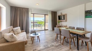 Uma sala de estar moderna com sofá, mesa de jantar, cadeiras e televisão.