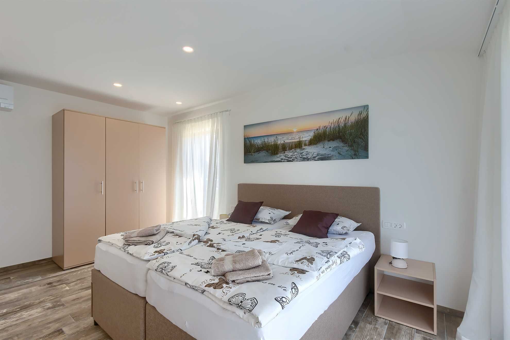 A bedroom with a bed, a nightstand, a wardrobe, and a painting on the wall.