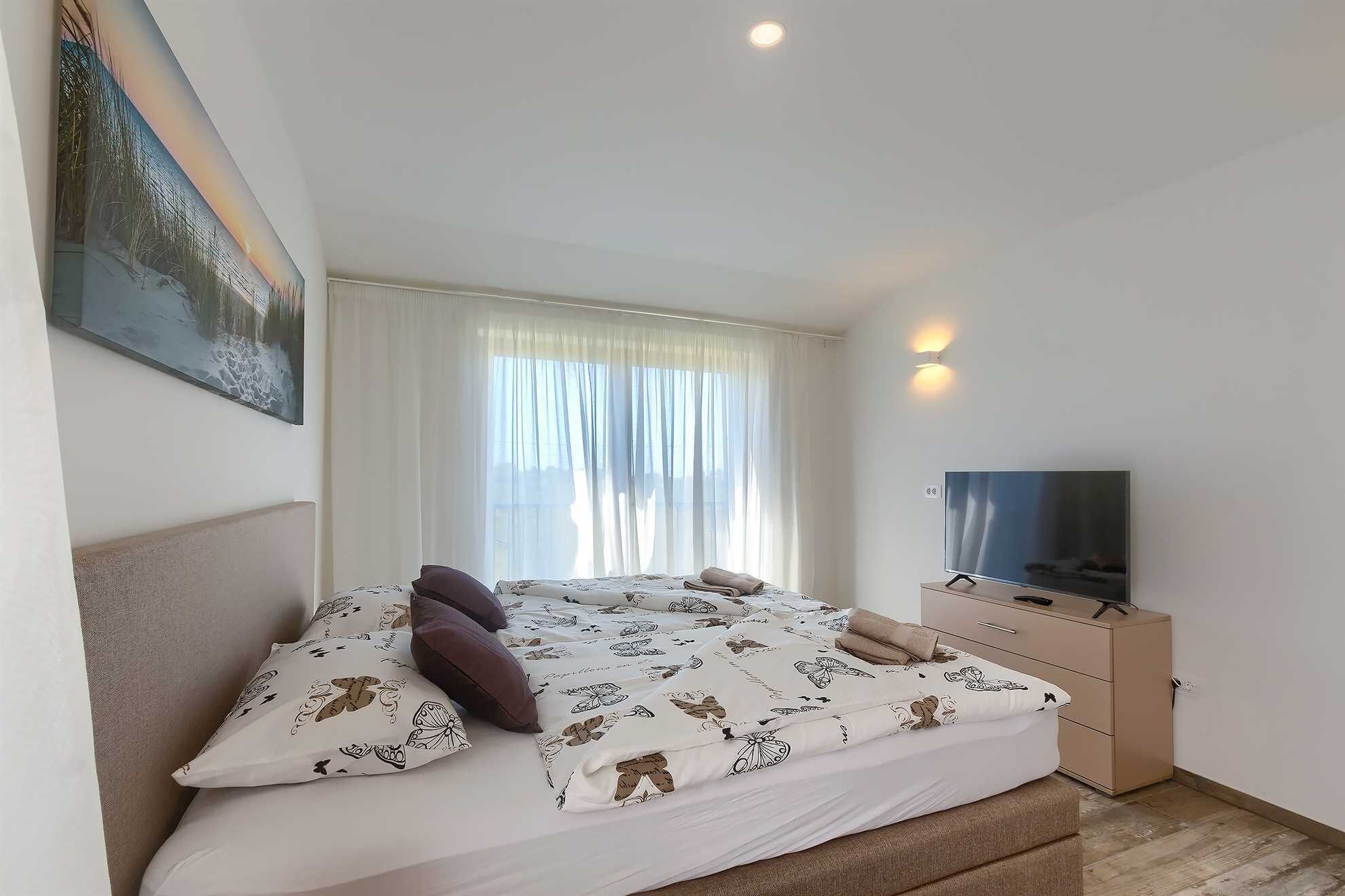 Une chambre à coucher avec un lit, une télévision et une fenêtre avec des rideaux.