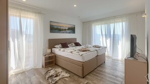 Quarto com uma cama grande, televisão e uma pintura na parede.