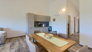 A modern kitchen with grey cabinets, a wooden dining table with a bowl, and a light-colored rug. - Brand New Modern apartment for 4+2 guests with shared pool (Novigrad)