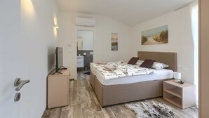 A modern bedroom with a bed, bedside table, and a TV. - Brand New Modern apartment for 4+2 guests with shared pool (Novigrad)