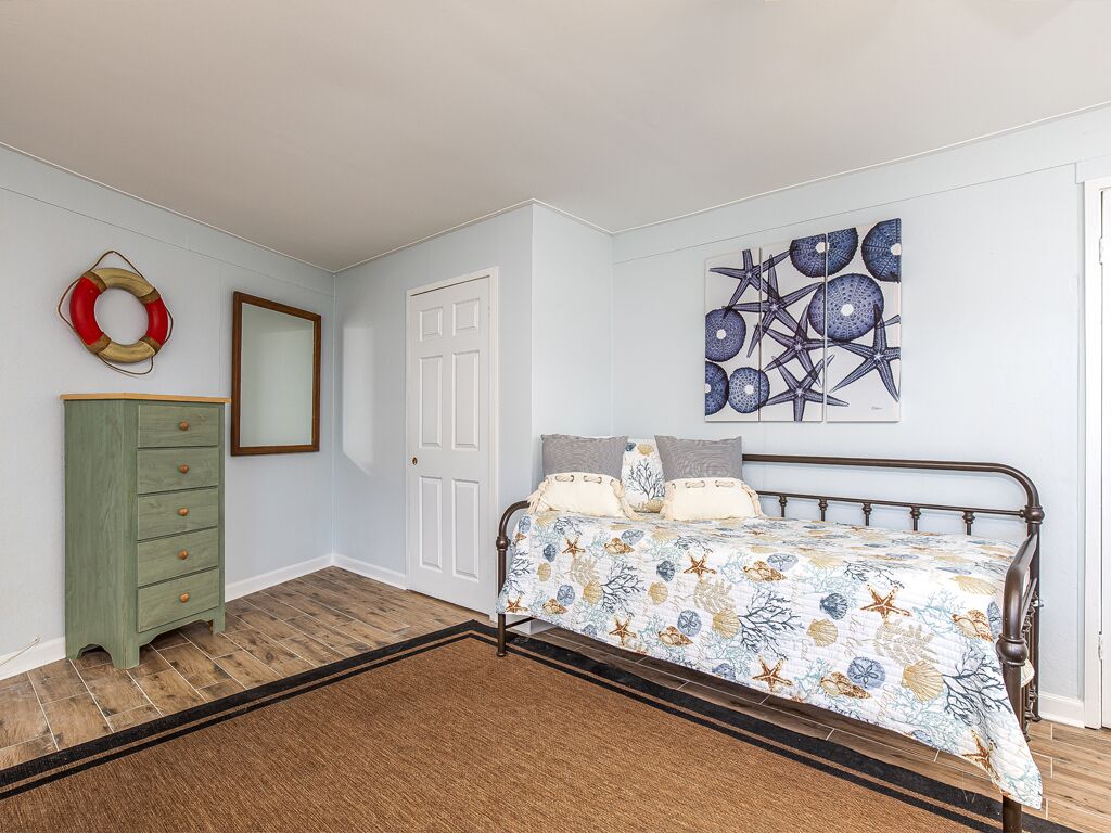 A bedroom with a bed, dresser, and artwork on the wall.