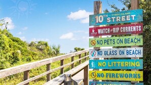 A wooden boardwalk with a sign listing beach rules including no pets, no glass, no littering, no fireworks, and no smoking or vaping. - Coastal Breezes by Tybee Vacation Rentals (Tybee Island)