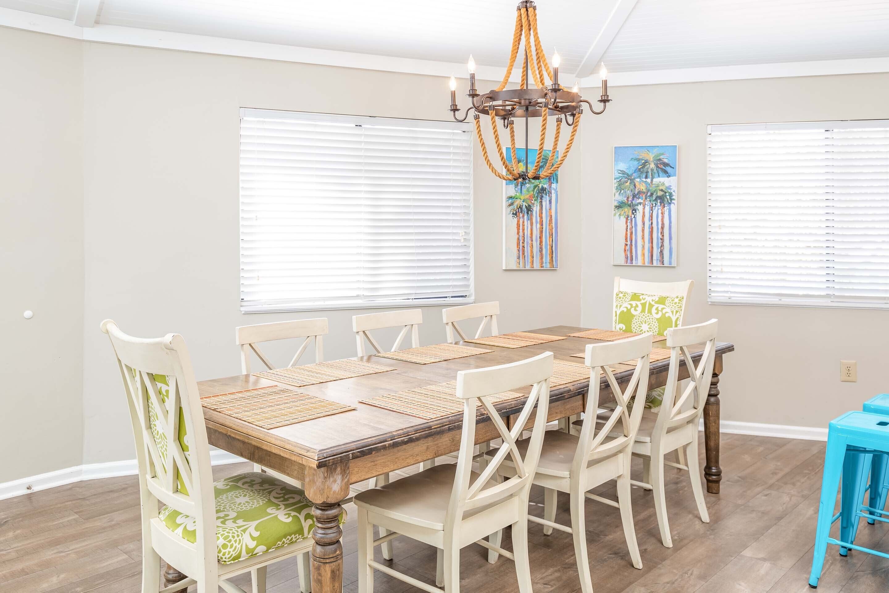 A dining area with a wooden table, white chairs, and a chandelier.